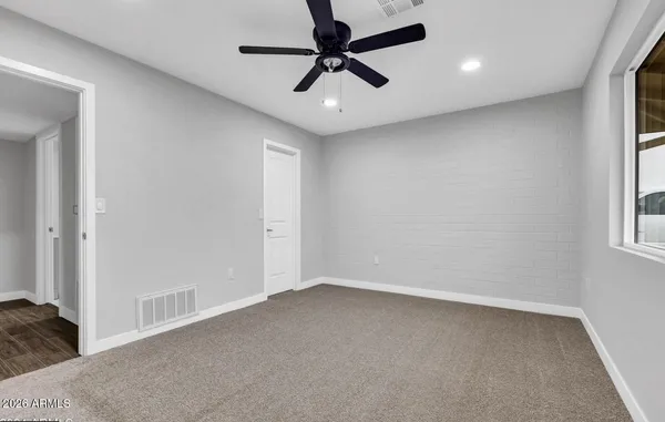 an empty room with a window and a fan
