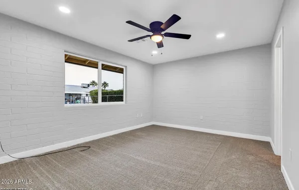 an empty room with a window and a ceiling fan