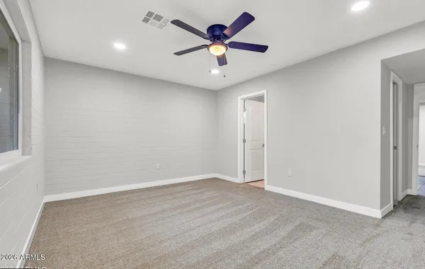 an empty room with closet and a ceiling fan
