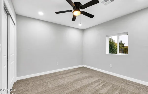 an empty room with a window and a fan