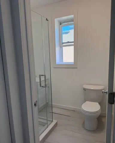 a white toilet sitting next to a shower