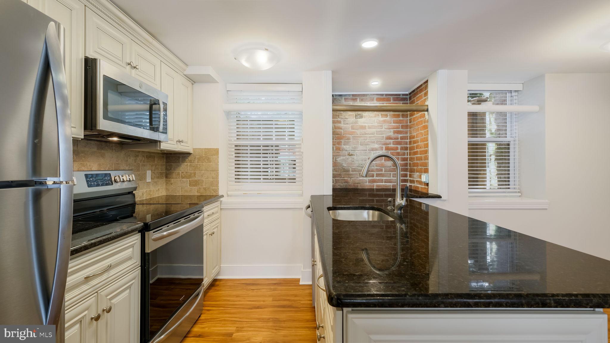 106 East State Street, Unit 4 Doylestown, PA 18901 - Photo 11 of 19 a kitchen with stainless steel appliances granite countertop a stove a sink and a microwave