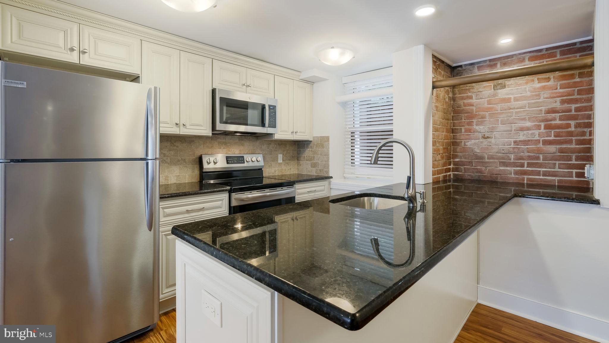 106 East State Street, Unit 4 Doylestown, PA 18901 - Photo 10 of 19 a kitchen with stainless steel appliances granite countertop a refrigerator a stove and a sink with wooden floor