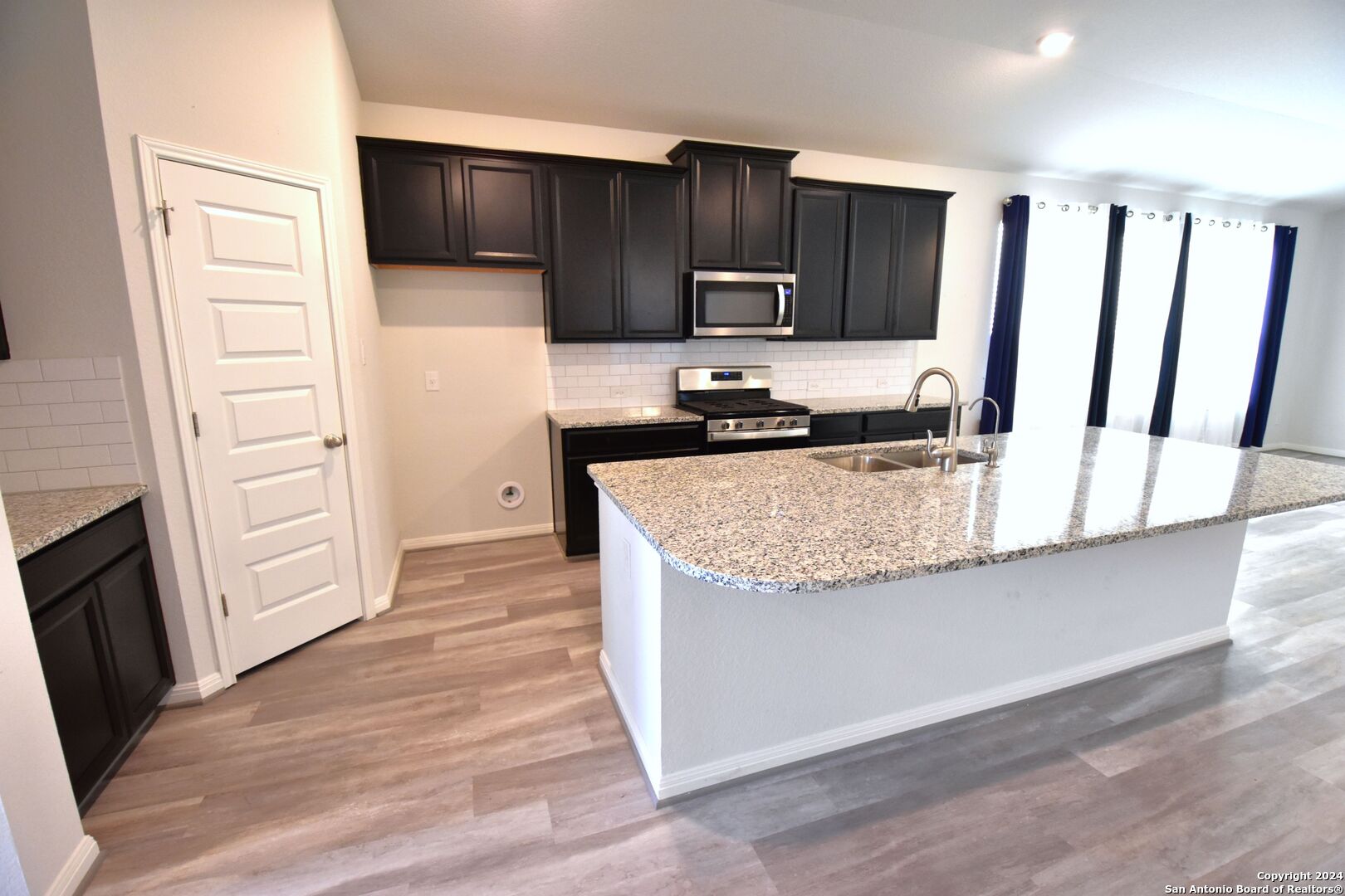 4923 Ranahan Pass St. Hedwig, TX 78152 - Photo 15 of 29 a kitchen with granite countertop a stove a sink and a refrigerator