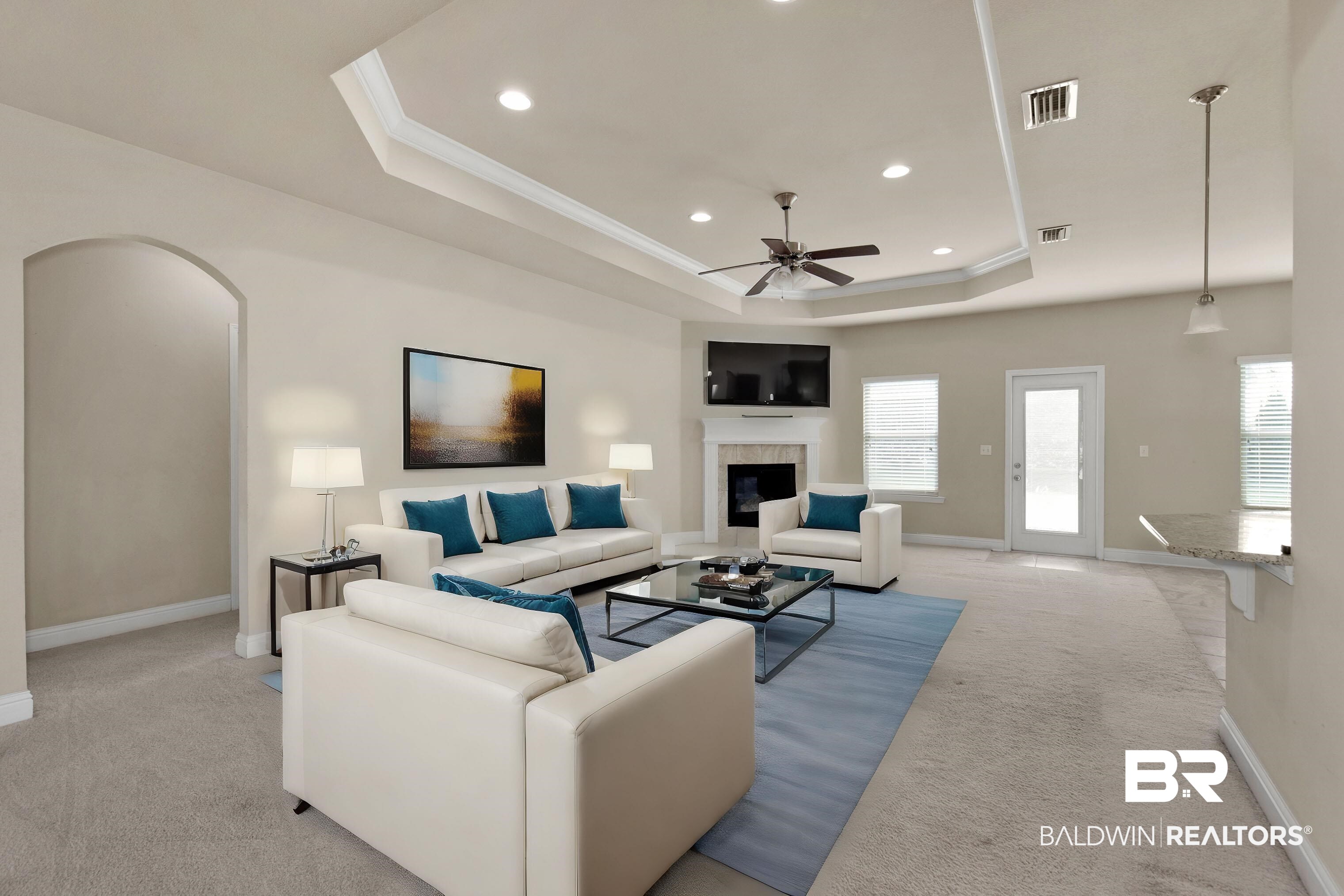 122 Open Field Drive Fairhope, AL 36532 - Photo 3 of 27 Carpeted living room with a tile fireplace, crown molding, ceiling fan, and a raised ceiling