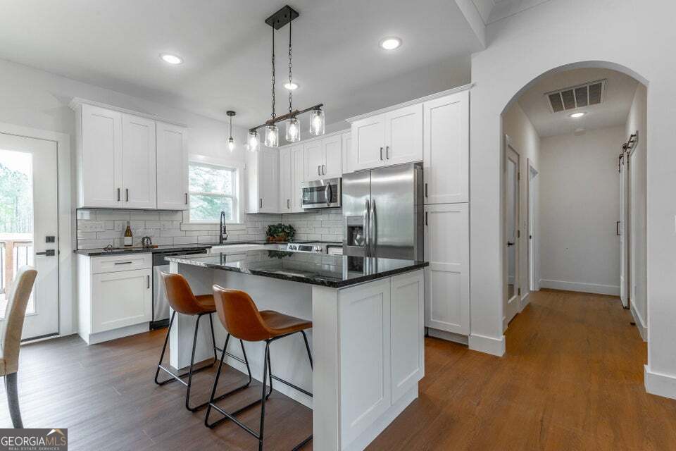 282 Glade Road Rossville, GA 30741 - Photo 9 of 20 a kitchen with stainless steel appliances granite countertop a refrigerator a stove a sink dishwasher a dining table and chairs with wooden floor
