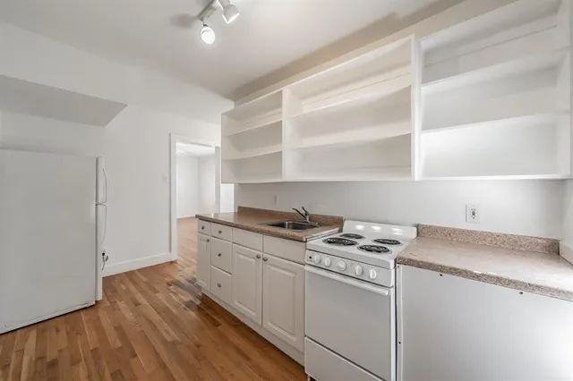 a kitchen with granite countertop a stove and a sink with cabinets
