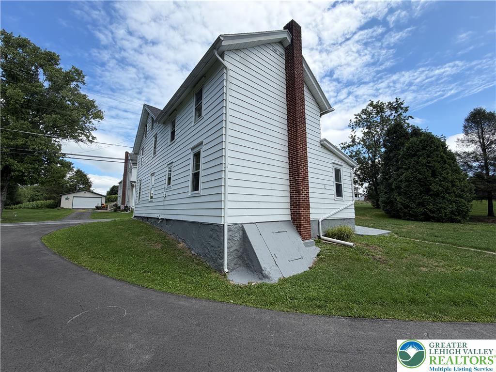 5720 Memorial Road Germansville, PA 18053 - Photo 4 of 29 A classic facade with white siding and a prominent brick chimney anchors a spacious property.
