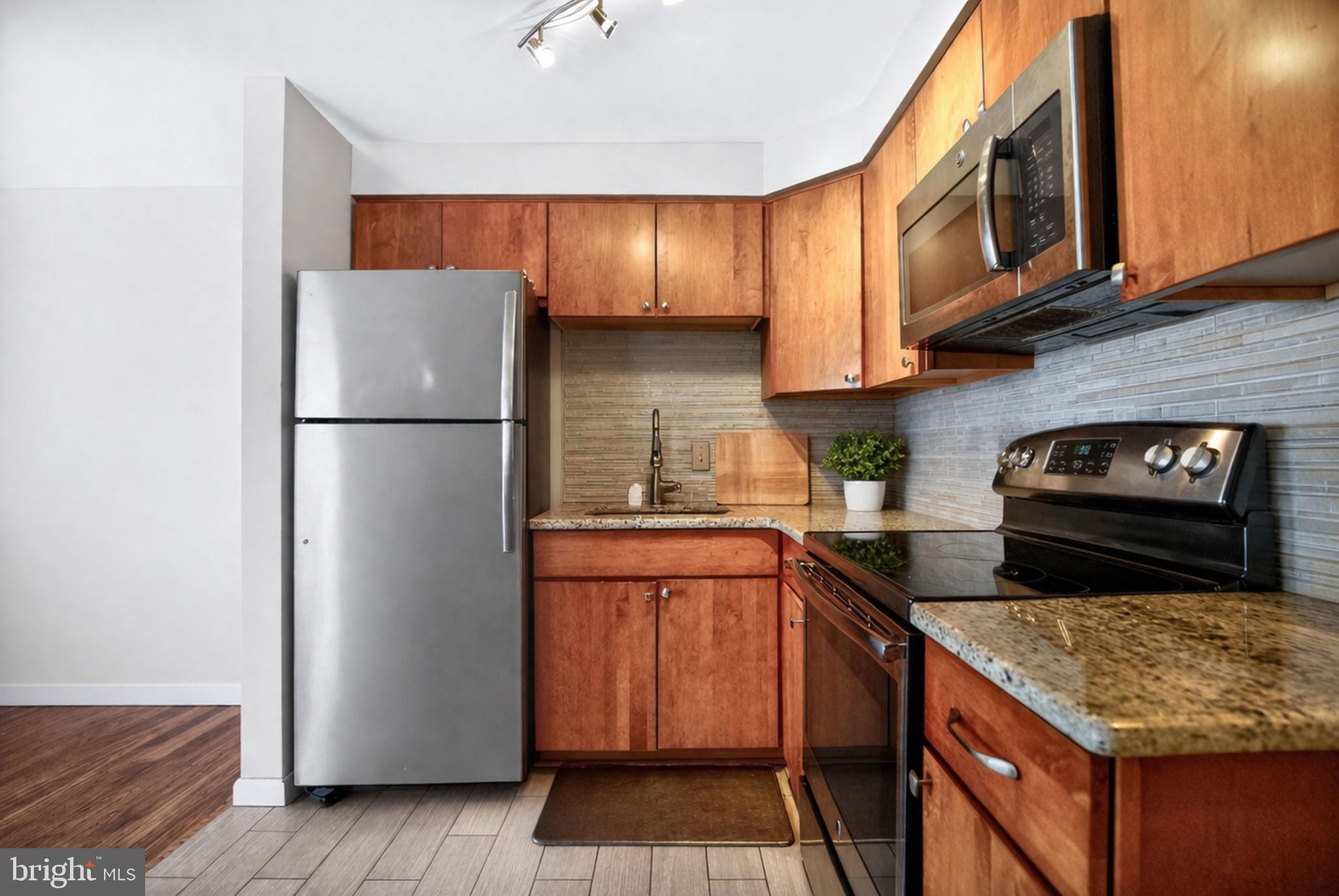 4401 Manayunk Avenue Philadelphia, PA 19128 - Photo 8 of 25 a kitchen with stainless steel appliances granite countertop a refrigerator a stove a sink and a microwave