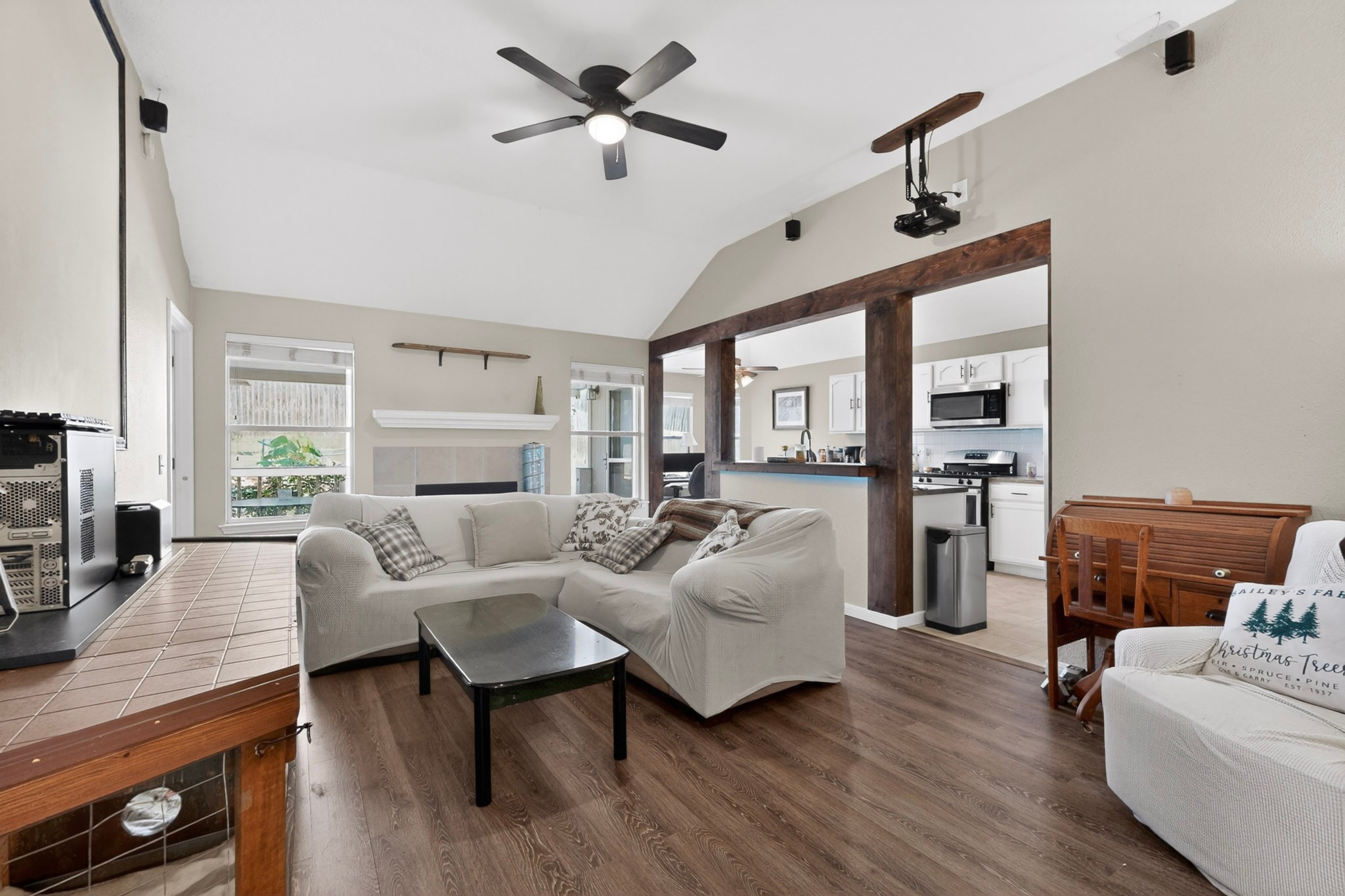 15104 Mimebark Way Austin, TX 78724 - Photo 1 of 38 Open-concept living area featuring vaulted ceilings, wood-finish flooring, a ceiling fan, and a fireplace with a mantel