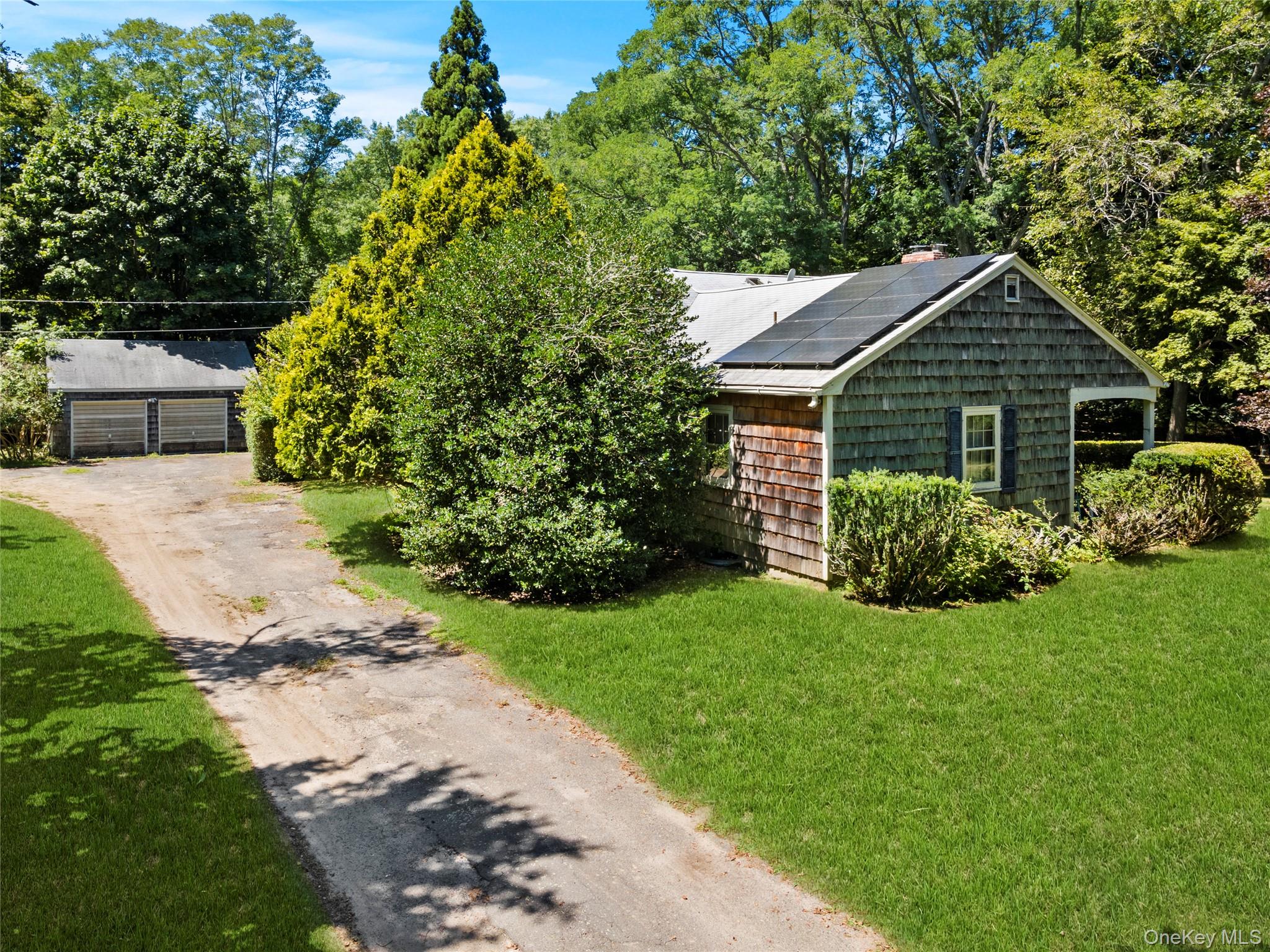 26 South Menantic Road Shelter Island, NY 11964 - Photo 31 of 42 View of front of home featuring solar panels, a front yard, and garage