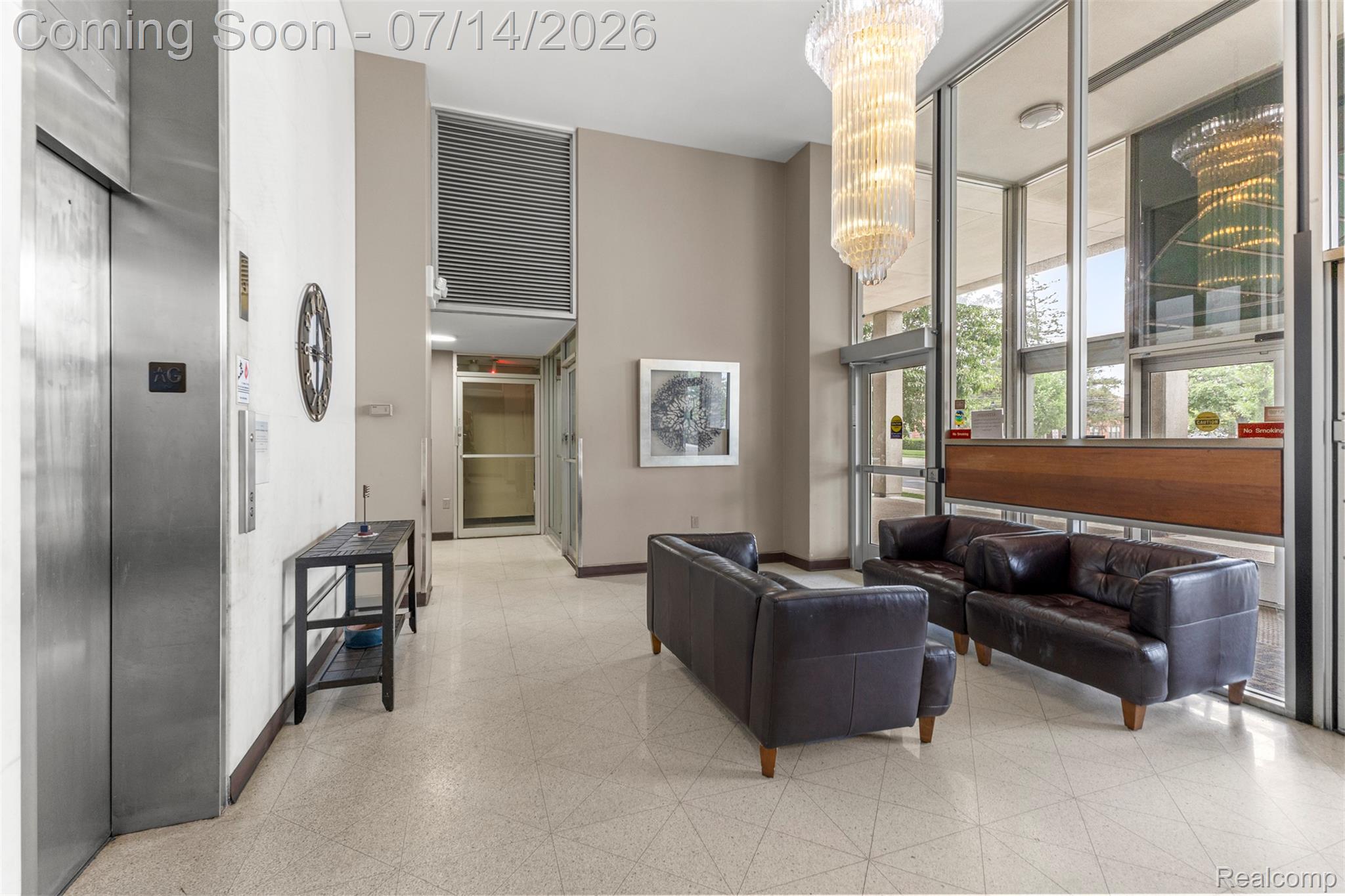 22700 Garrison Street, Unit 707 Dearborn, MI 48124 - Photo 19 of 22 Lobby featuring a large glass and chrome chandelier, full-height windows, terrazzo flooring, and a stainless steel elevator