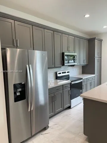 a kitchen with stainless steel appliances granite countertop a refrigerator a stove a sink and a microwave