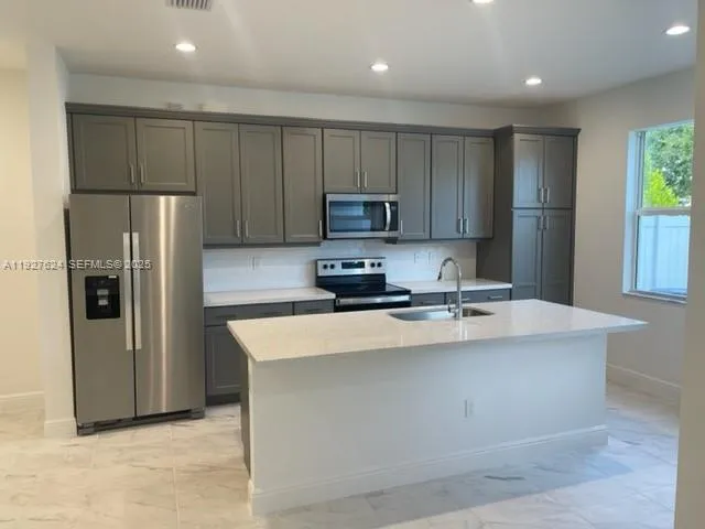 a kitchen with stainless steel appliances granite countertop a refrigerator a stove a sink and a microwave