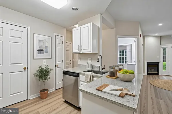 a kitchen with stainless steel appliances granite countertop a refrigerator a sink dishwasher stove and white cabinets with wooden floor