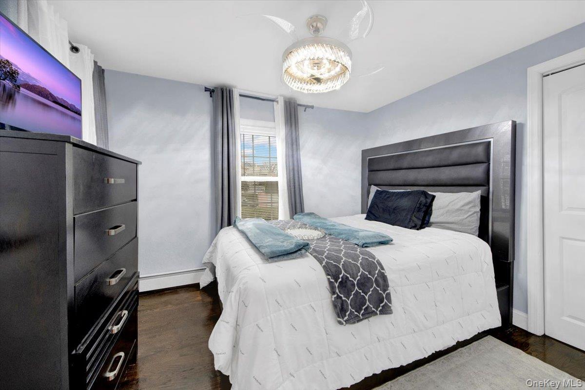 75 West Kingsbridge Road Mount Vernon, NY 10550 - Photo 18 of 37 Bedroom with dark wood-style flooring, a baseboard radiator, and a chandelier