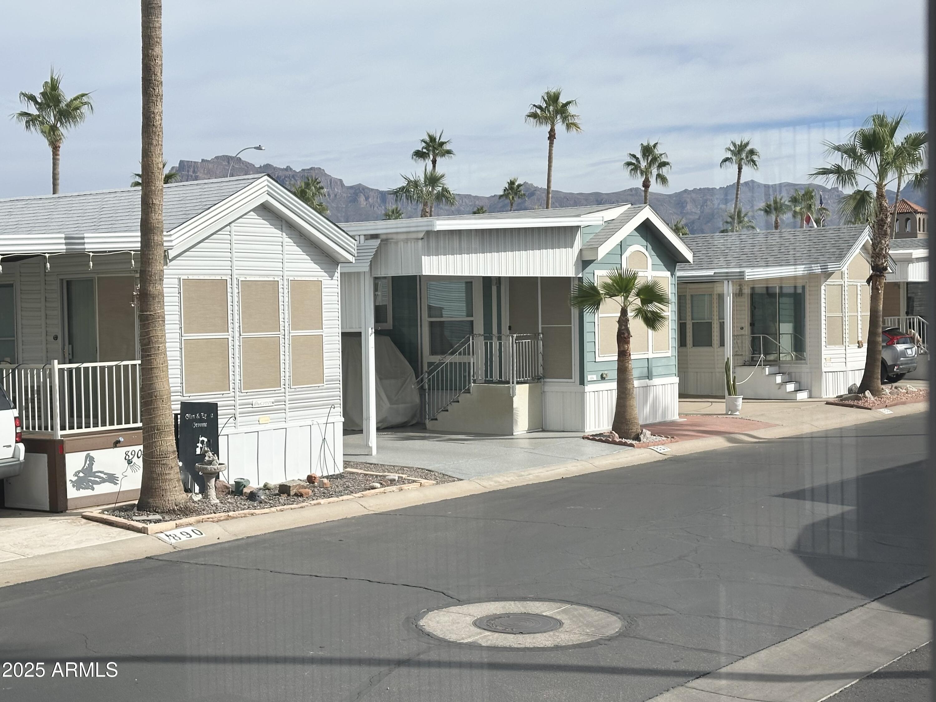3710 South Goldfield Road, Unit 1052 Apache Junction, AZ 85119 - Photo 11 of 48 a view of a white house with large windows and a small yard
