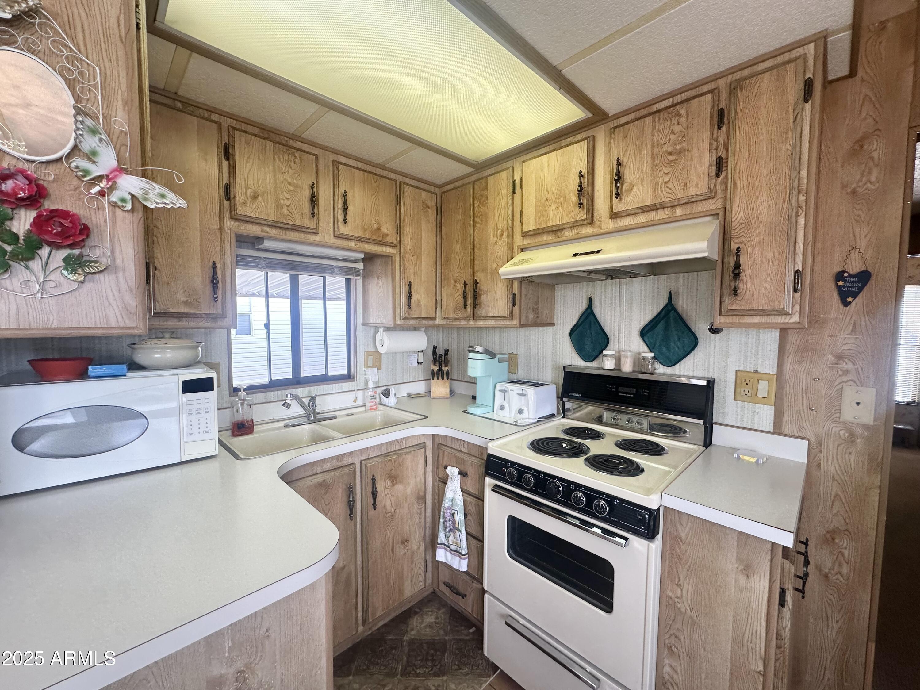 3710 South Goldfield Road, Unit 1052 Apache Junction, AZ 85119 - Photo 18 of 48 a kitchen with stainless steel appliances a stove a sink and a refrigerator