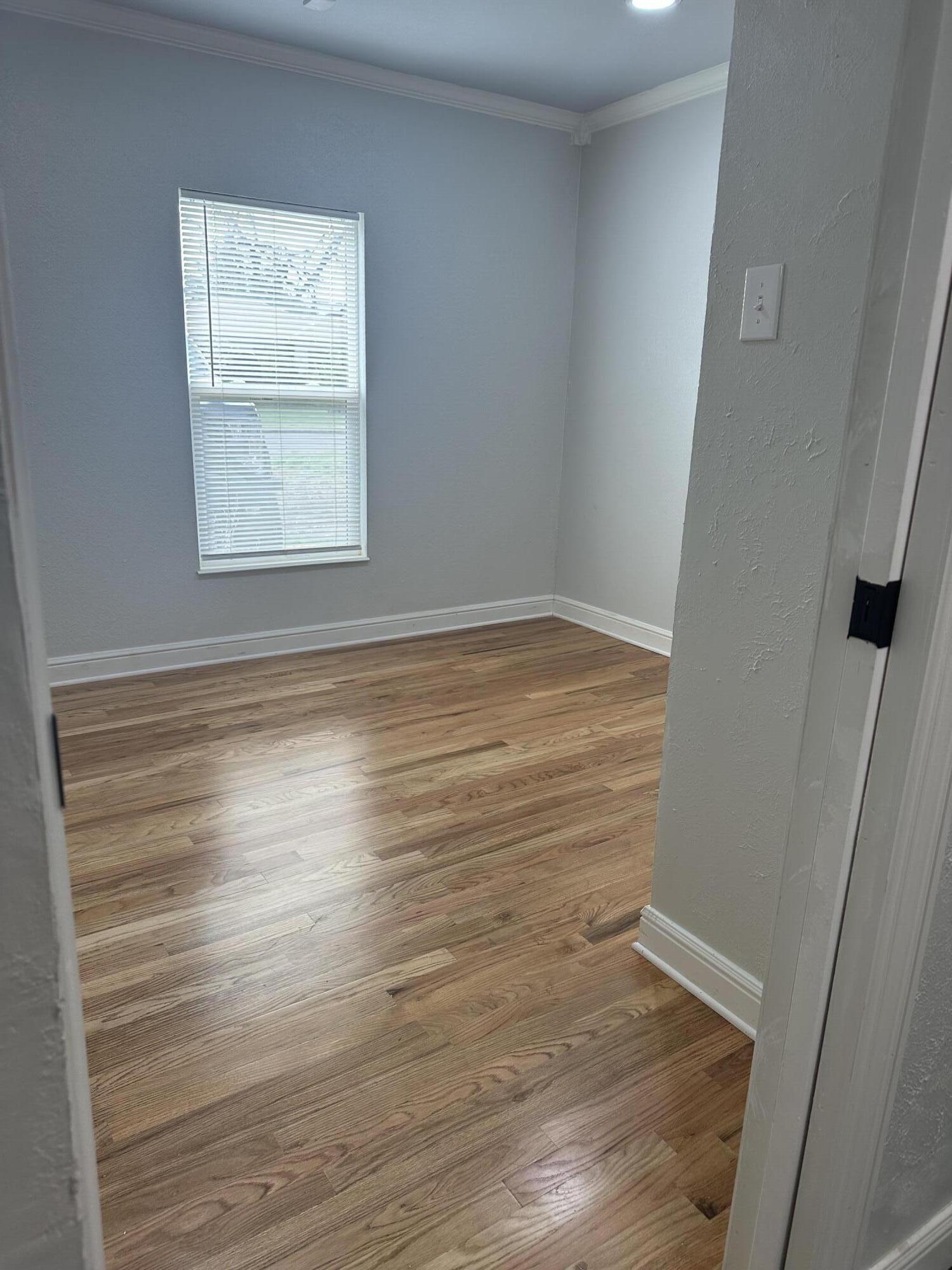 2712 30th Street Lubbock, TX 79410 - Photo 16 of 26 a view of an empty room with wooden floor and a window