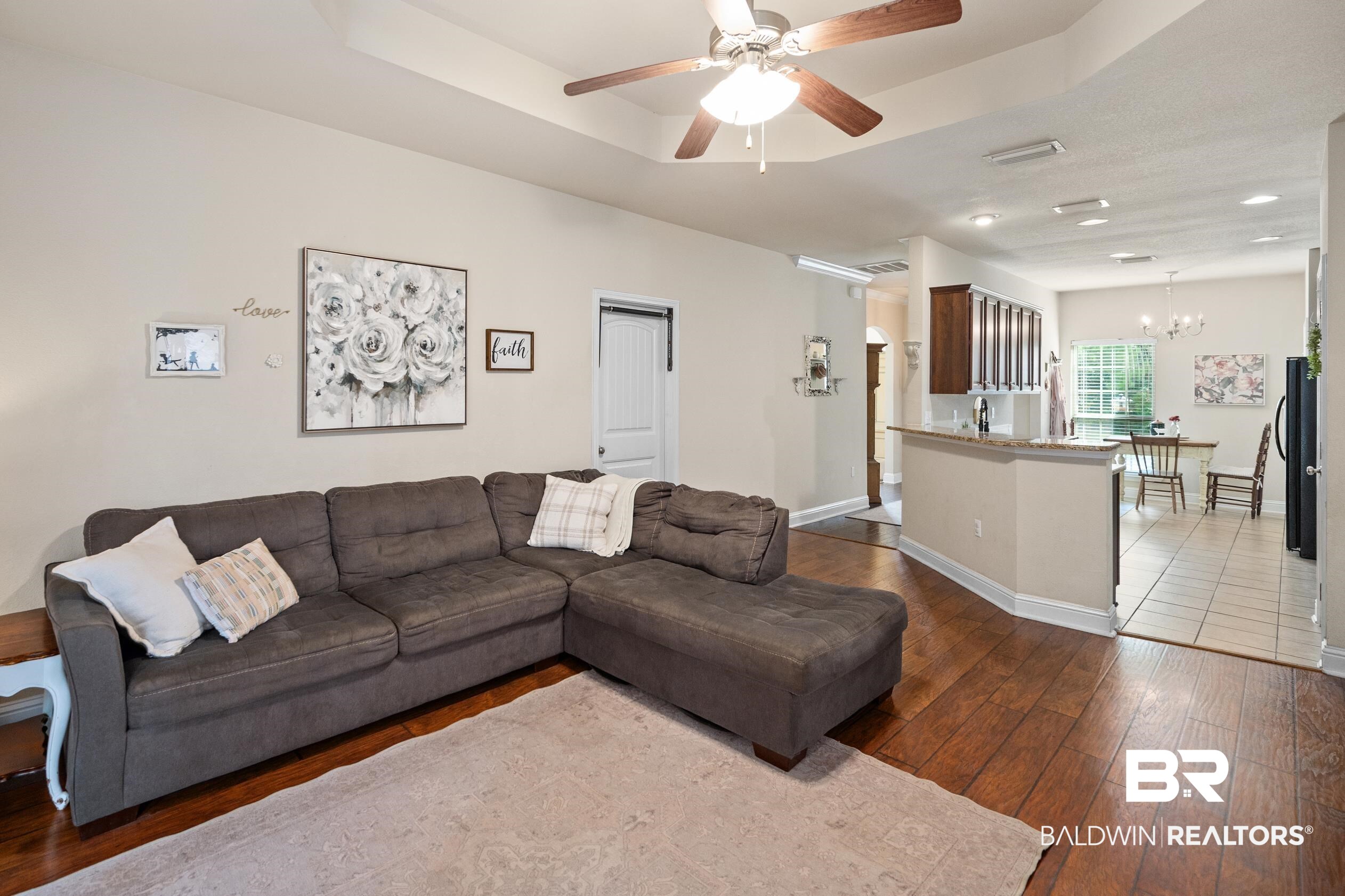 745 Bonaventure Street Fairhope, AL 36532 - Photo 4 of 36 Living room with dark wood-type flooring, a raised ceiling, and ceiling fan with notable chandelier