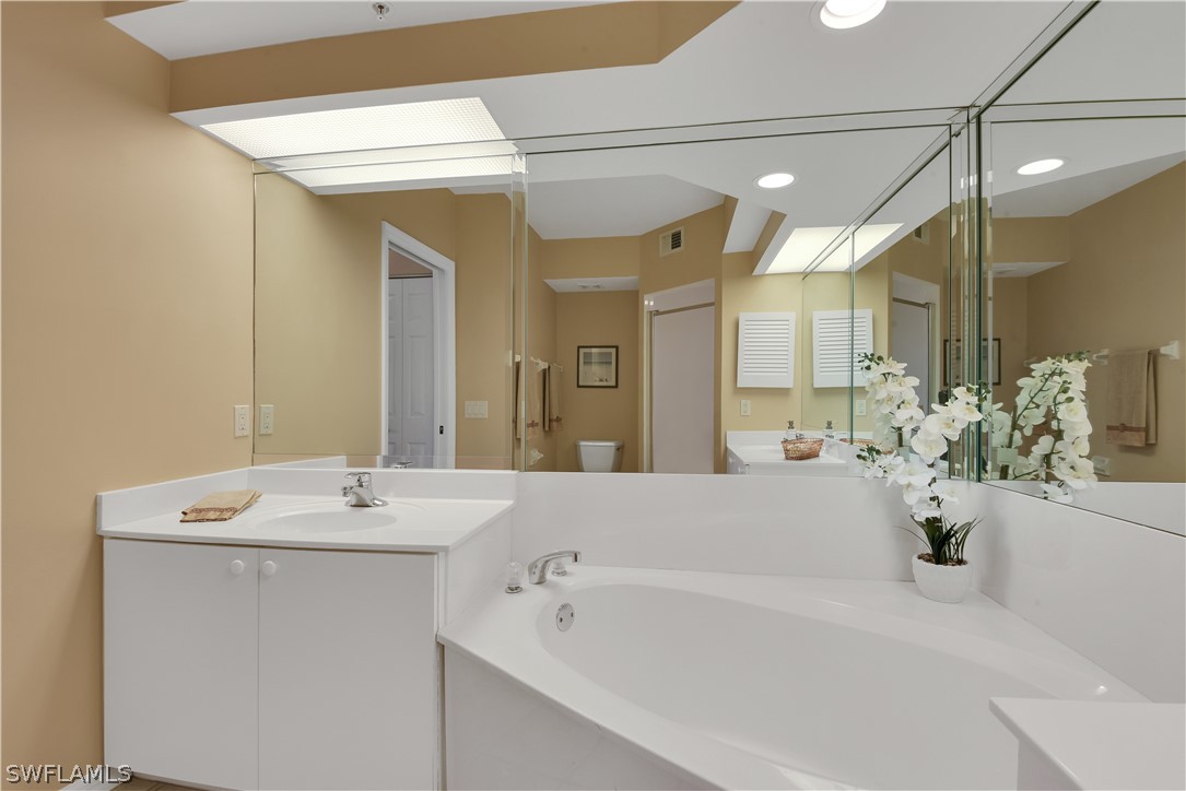 6838 Lantana Bridge Road, Unit 102 Naples, FL 34109 - Photo 18 of 34 a bathroom with a tub sink and mirror