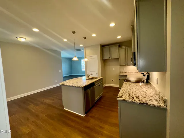 a view of kitchen with kitchen island wooden floor and stainless steel appliances