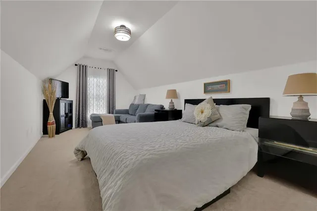 a spacious bedroom with a bed and a lamp on table