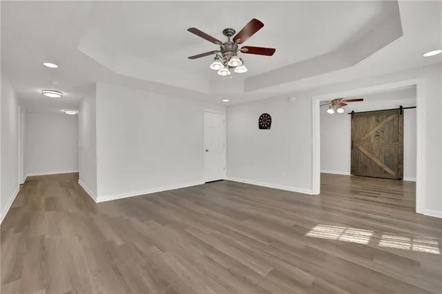 a view of an empty room with wooden floor and a ceiling fan