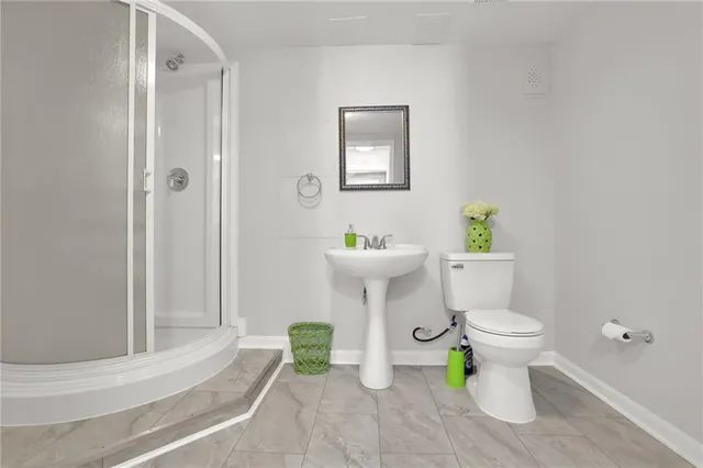 a white toilet sitting next to a bathroom sink and a shower