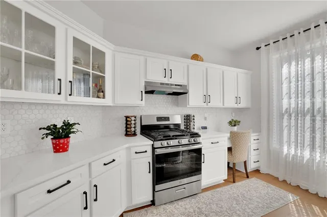 a kitchen with stainless steel appliances white cabinets and wooden floor
