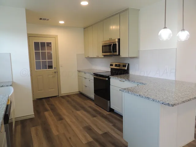 a kitchen with stainless steel appliances granite countertop a sink a stove and a refrigerator