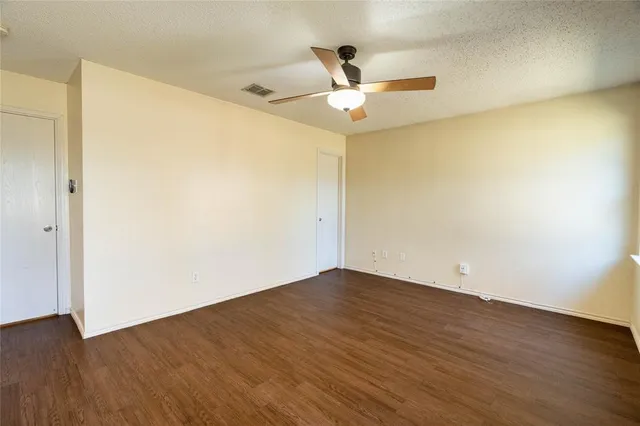 an empty room with wooden floor fan and windows