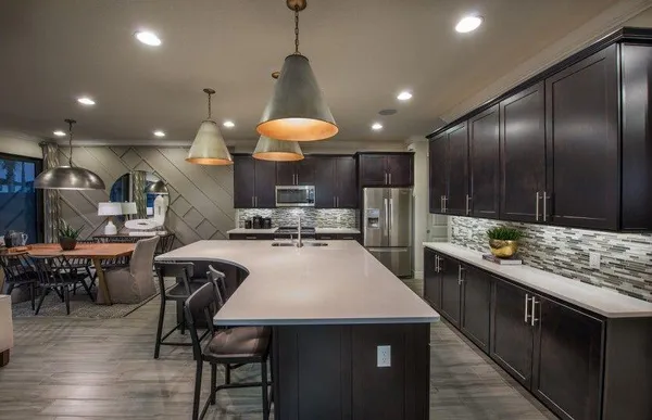 a kitchen with stainless steel appliances kitchen island granite countertop a stove a sink a oven a dining table and chairs with wooden floor