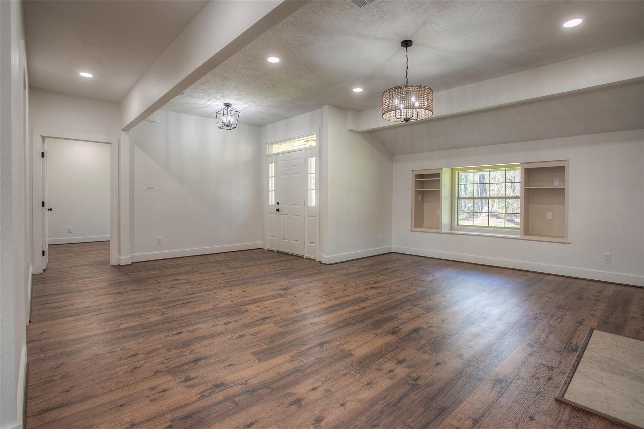83 Dahlia Road Huntsville, TX 77320 - Photo 11 of 49 an empty room with wooden floor chandelier and windows