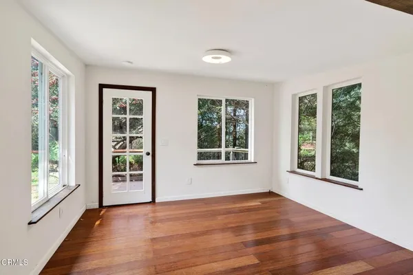 a view of an empty room with wooden floor and windows