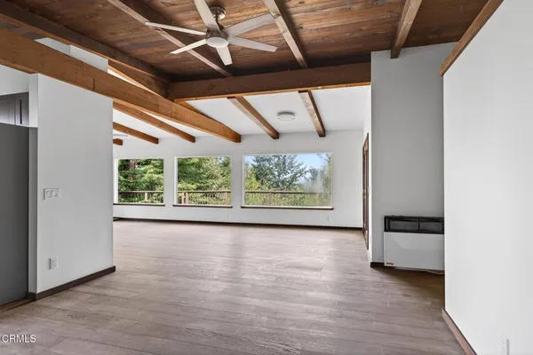 a view of a big room with wooden floor and windows