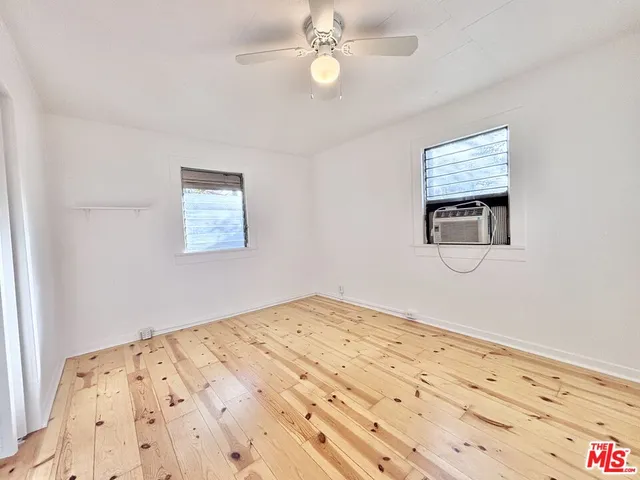 a view of a bedroom with wooden floor and a ceiling fan