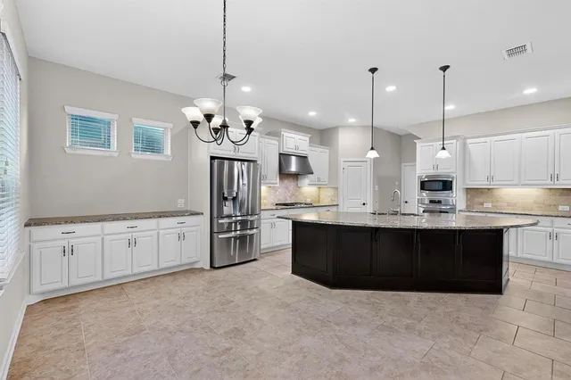 a large kitchen with granite countertop a stove a sink a refrigerator and a granite counter tops