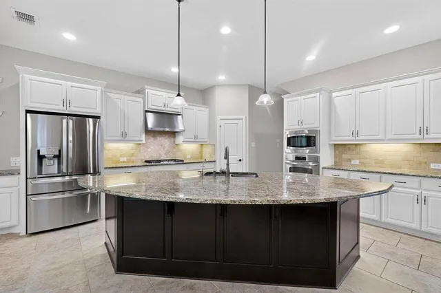 a kitchen with stainless steel appliances granite countertop a sink a center island a stove and a refrigerator