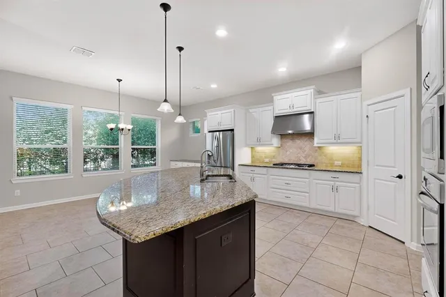 a kitchen with granite countertop kitchen island white cabinets and stainless steel appliances