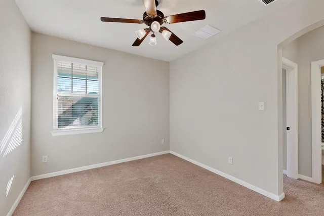 an empty room with windows and fan