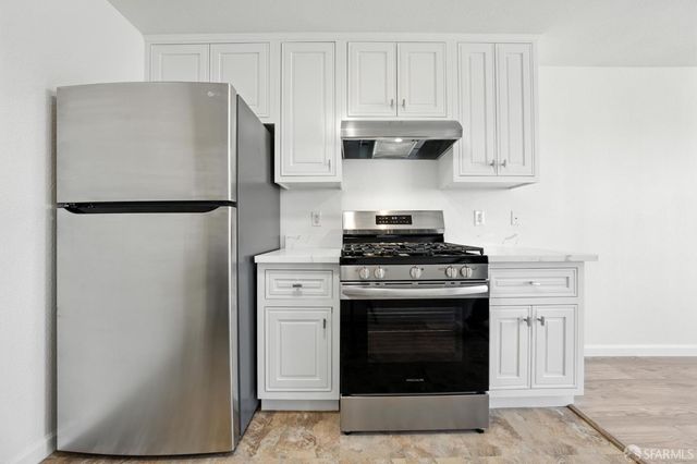a kitchen with stainless steel appliances white cabinets and a refrigerator