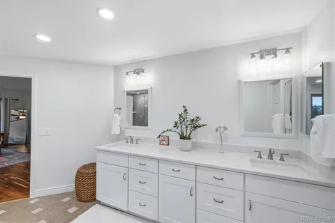 a bathroom with double vanity sinks a vanity a lamp and a mirror