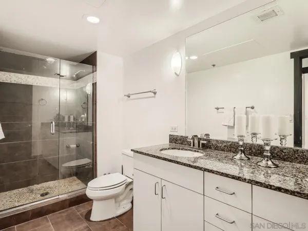 a bathroom with a granite countertop sink a toilet and shower