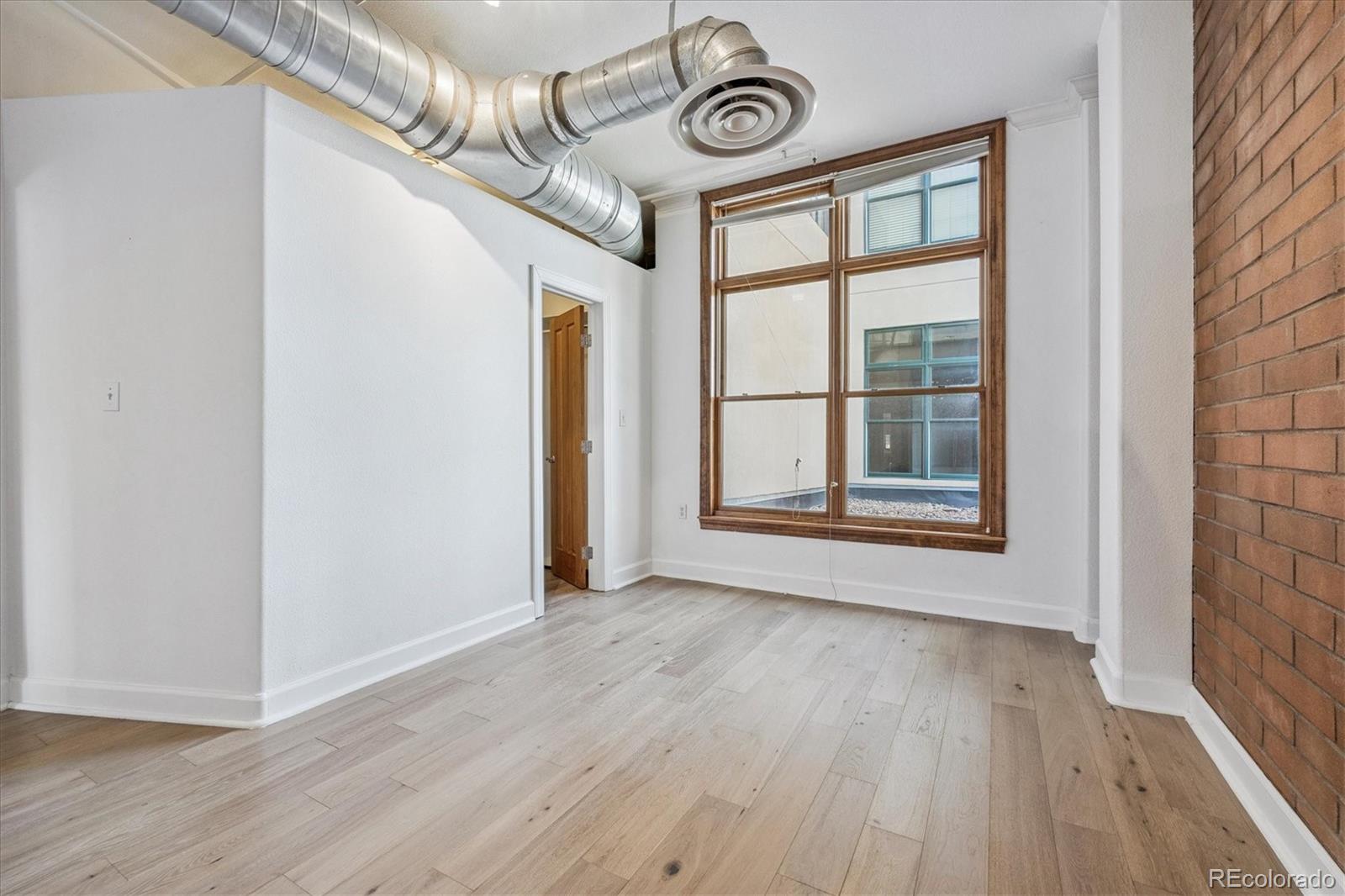2245 Blake Street, Unit F Denver, CO 80205 - Photo 28 of 38 a view of an empty room with wooden floor and a window