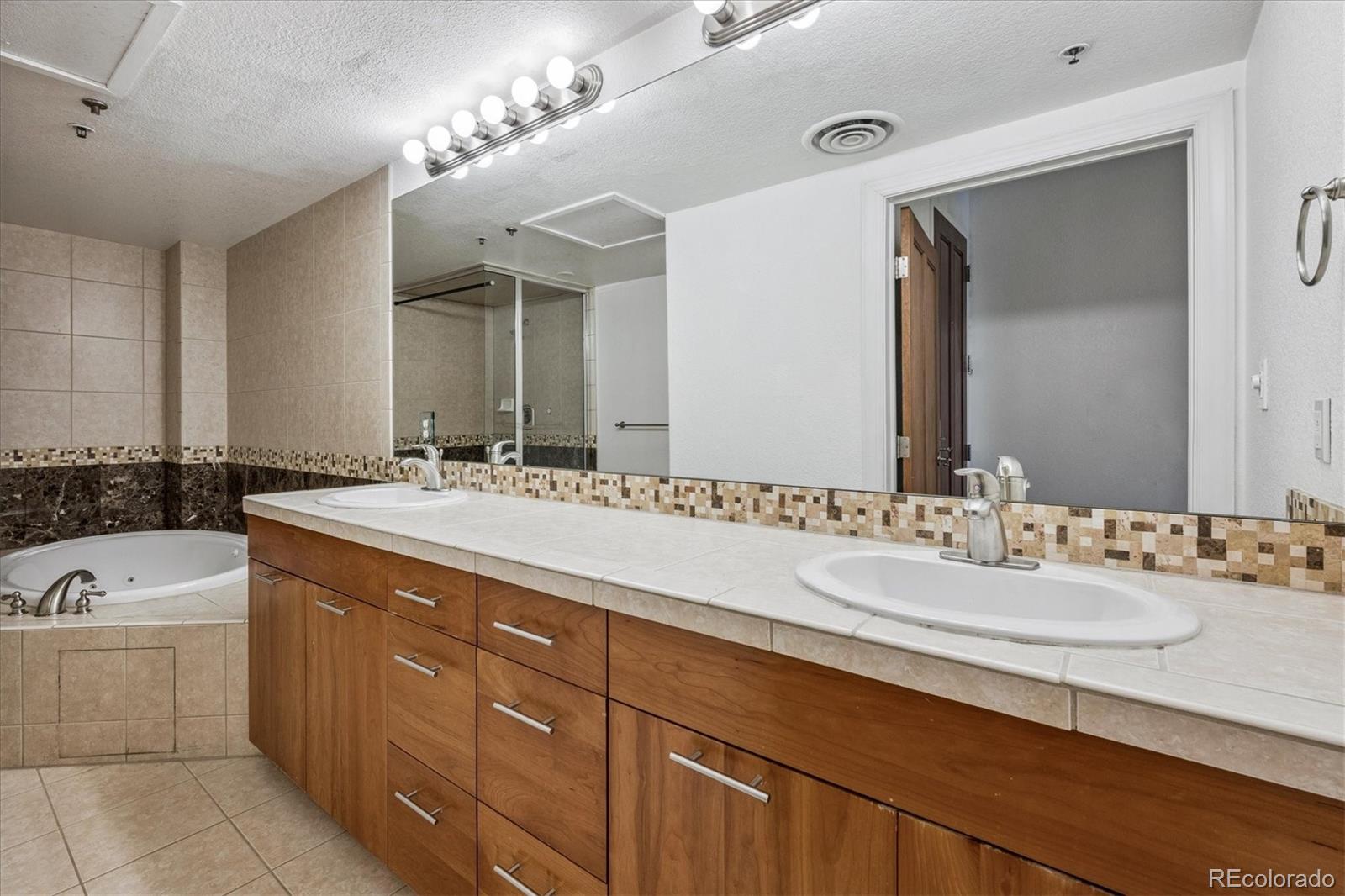2245 Blake Street, Unit F Denver, CO 80205 - Photo 30 of 38 a bathroom with a double vanity sink a mirror and a bathtub