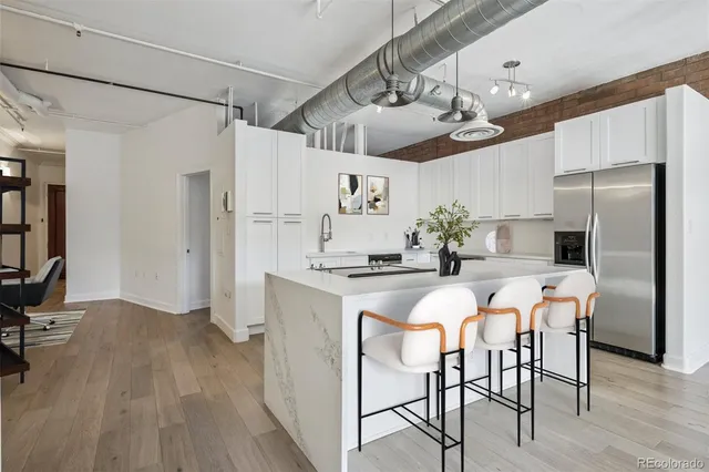 a kitchen with stainless steel appliances a refrigerator a stove a dining table and chairs with wooden floor