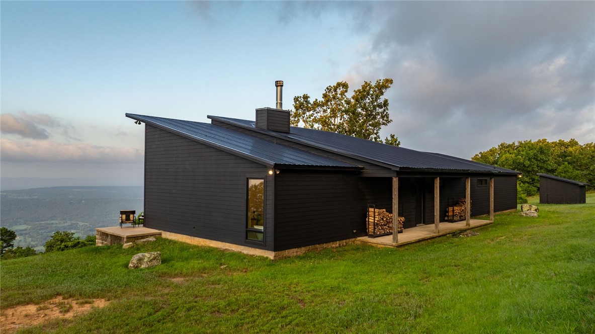 11334 Pool Holw Road Dardanelle, AR 72834 - Photo 2 of 50 Modern architectural exterior featuring a dark facade, sloped metal roof, and a covered porch with natural wood columns