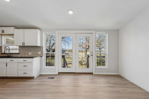 a view of an empty room with kitchen and window
