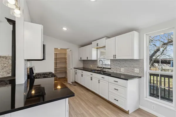 a kitchen with granite countertop a sink stove and cabinets